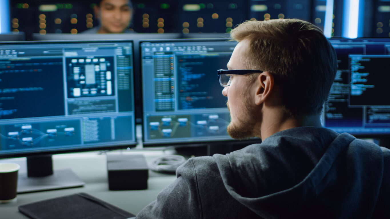 IT worker looking at code working on cyber security for a broadband network