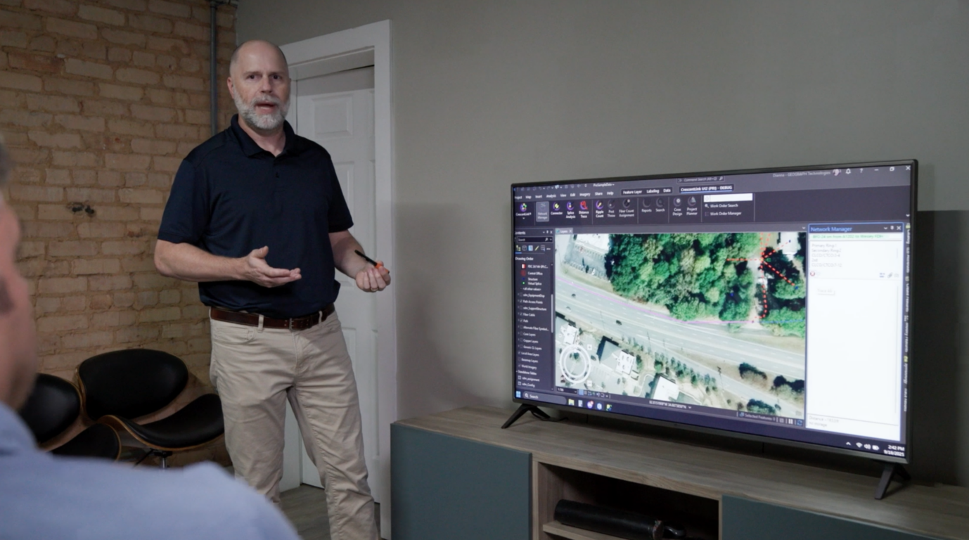 GEOGRAPH team member Tim Sexton showing new CrescentLink features on a TV screen to a meeting